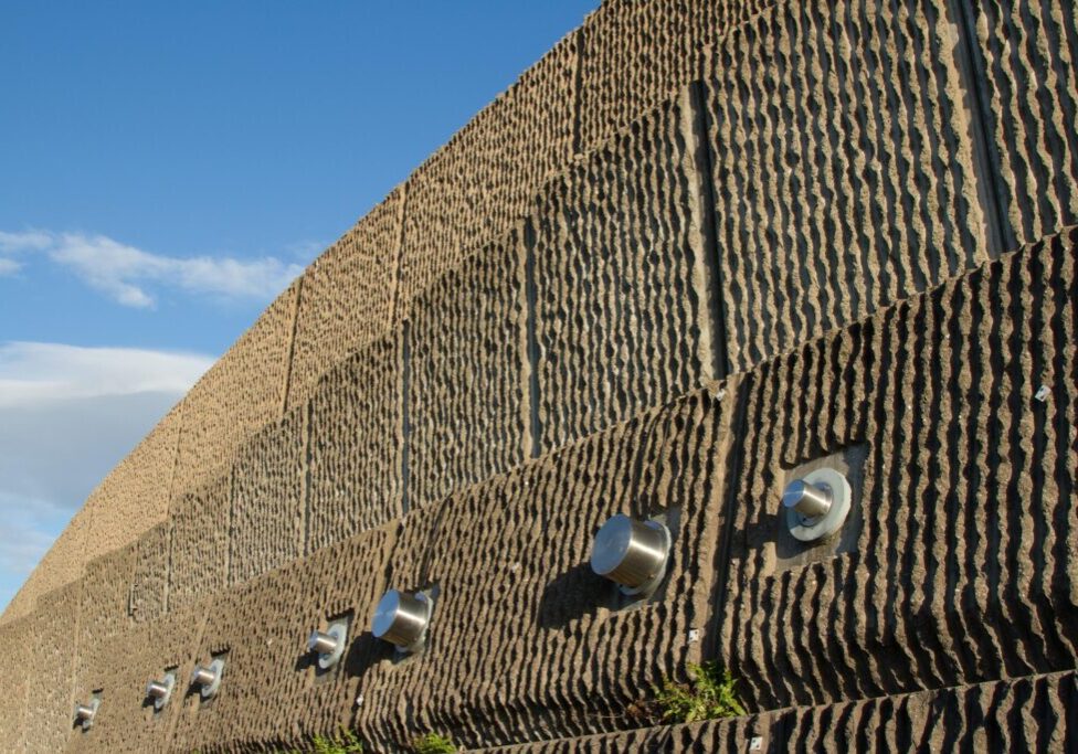 a concrete wall with stainless circular metal on the bottom