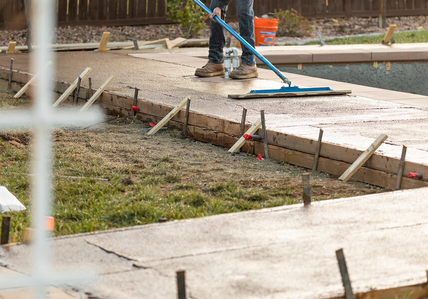 construction worker smoothing wet cement with trowel tool